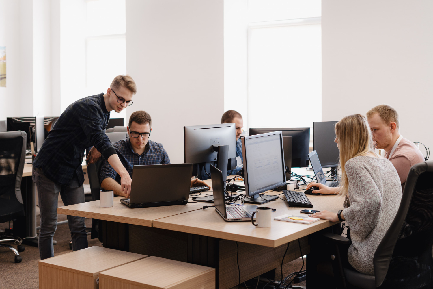 Collaborative team of developers in a modern workspace solving tech issues and delivering IT support